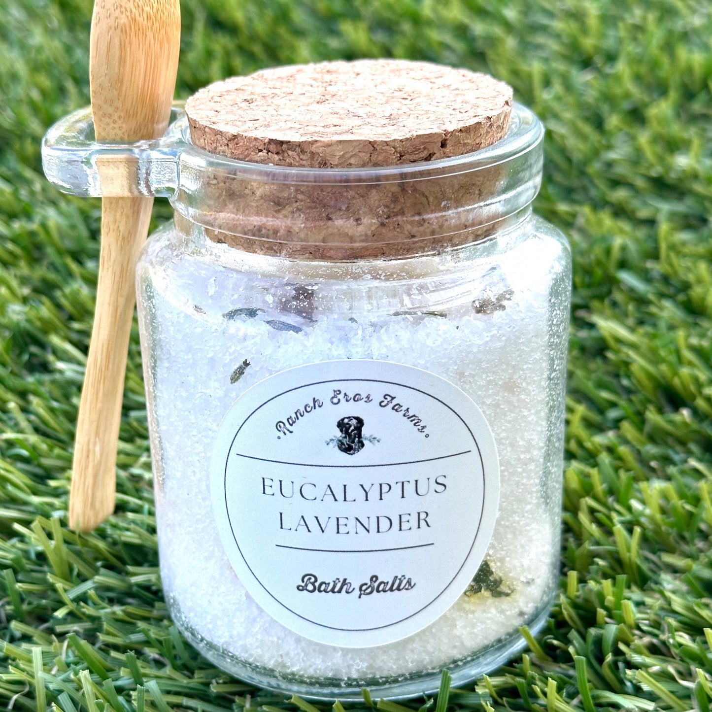 eucalyptus lavender bath salts in glass jar with wooden spoon on grass